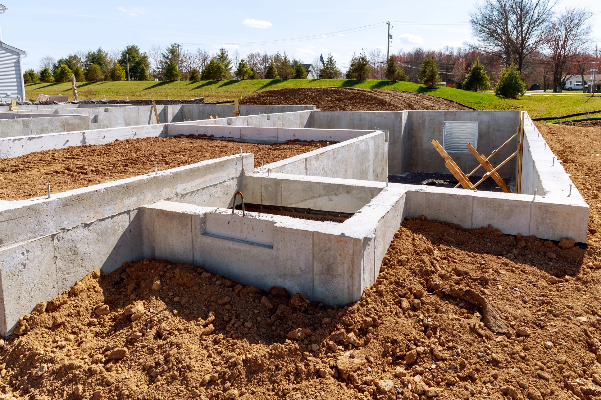 Chantier de construction résidentielle en cours, fondations en béton coulé avec murs de soubassement et semelles filantes