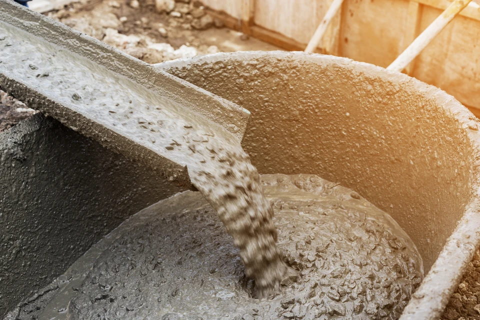 Chantier de construction en extérieur avec coulage de béton frais depuis une benne de camion toupie vers des coffrages en bois