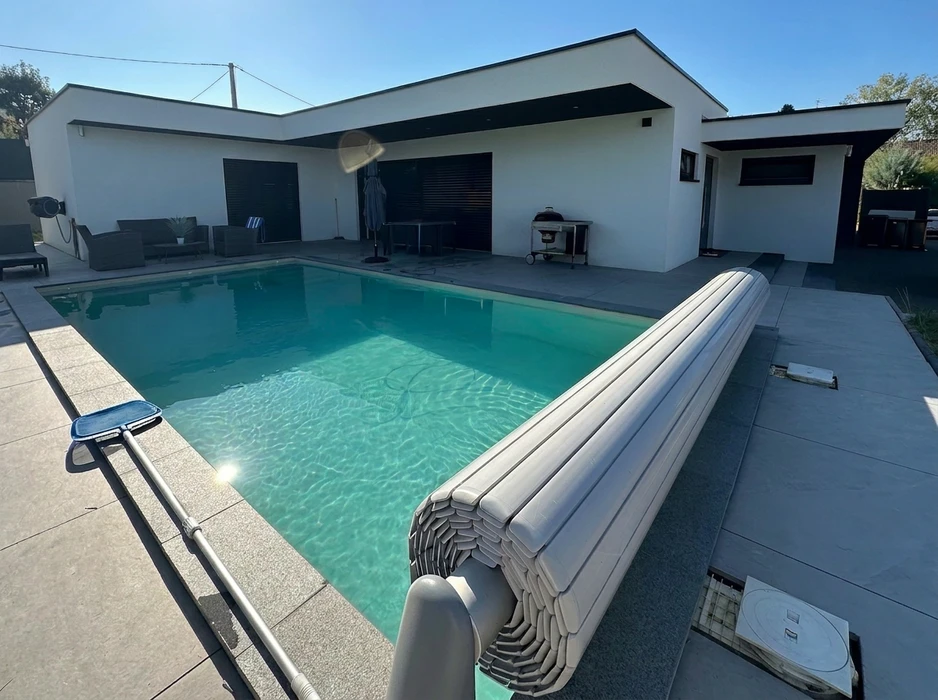 Piscine rectangulaire extérieure avec eau turquoise, entourée d'une terrasse en dalles grises