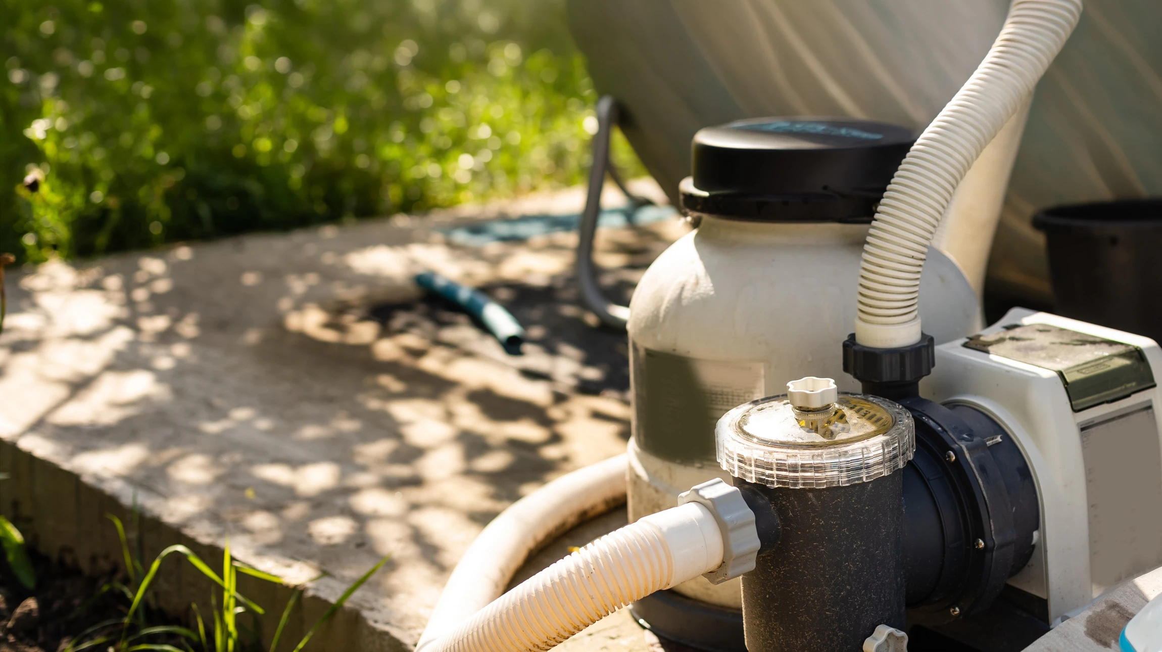 Gros plan sur un technicien en tenue professionnelle de chantier effectuant l'installation de tuyauteries et de composants de filtration dans une fosse technique adjacente à une piscine en construction. La filtration doit montrer des éléments spécifiques: filtre à sable ou cartouche, pompe de circulation, vannes de régulation, tuyauterie de PVC blanc ou gris. L'arrière-plan doit montrer une partie de la piscine en béton en cours de finition. La scène doit être réelle, bien éclairée, professionnelle, montrant le savoir-faire technique du maçon-pisciniste.